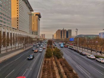 Traffic on road amidst buildings in city against sky