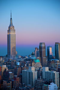 Modern buildings in city against sky during sunset