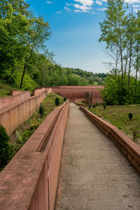 Footpath by bridge against sky