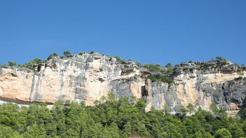 Low angle view of rocks against clear blue sky