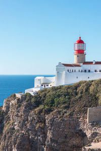 Lighthouse by sea against clear sky