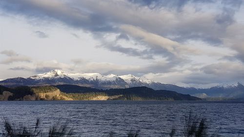 Scenic view of lake by snowcapped mountains against sky