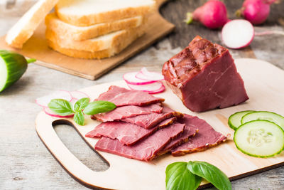 Fresh sliced marbled beef pastrami and vegetables on a cutting board. american delicacy