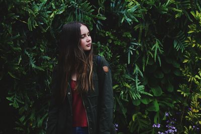 Young woman standing by tree in forest