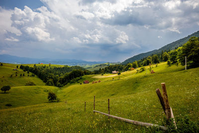 Scenic view of grassy field against cloudy sky