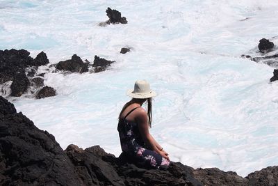 Woman relaxing by sea on rock