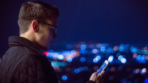 Side view of man using phone at night