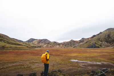 Rear view of man walking on mountain against clear sky