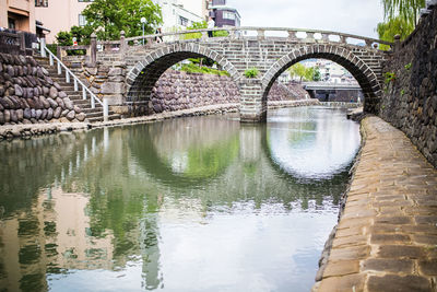 Arch bridge over river in city against sky