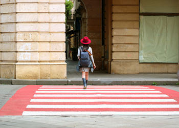 Rear view of woman with backpack walking on road