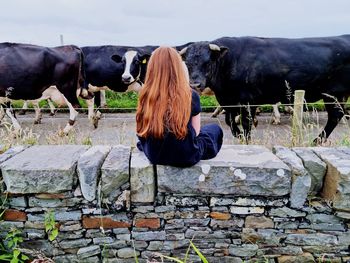 Rear view of woman standing by stone wall