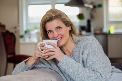 Portrait of happy woman having coffee at home