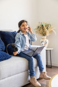 Young woman using mobile phone while sitting on sofa at home