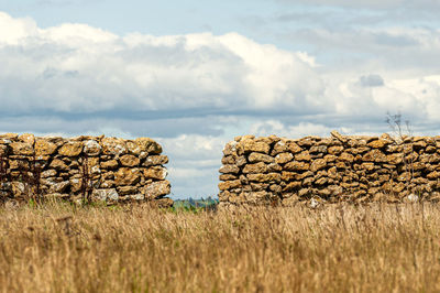 Stack of hay bales on field against sky