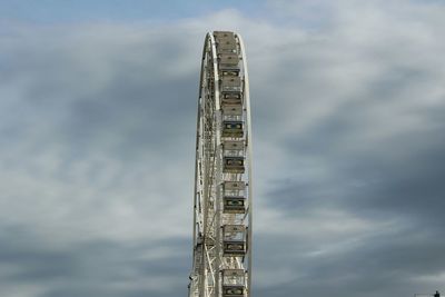 Low angle view of ferris wheel against cloudy sky