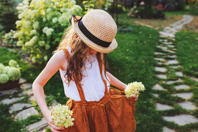 Midsection of woman wearing hat against plants