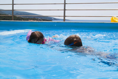 Cute sibling swimming in pool