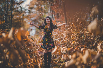 Portrait of young woman standing by tree