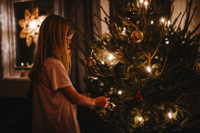 Girl decorating christmas tree at home