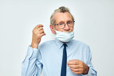 Portrait of senior man wearing mask against white background