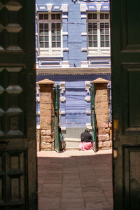 View of residential building. woman sits outside colonial building in potosí, bolivia 