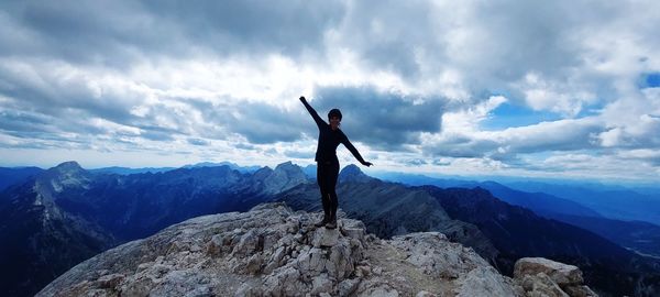 Rear view of man jumping on mountain against sky