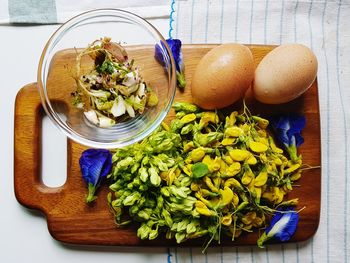 Directly above shot of flower buds and egg on cutting board at table