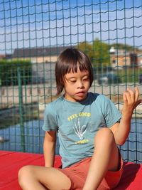 Full length of young child sitting by fence