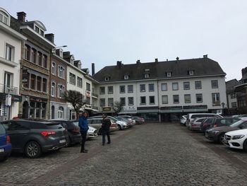 Cars on street by buildings against sky in city