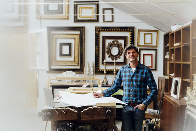 Smiling mature man standing by workbench in studio