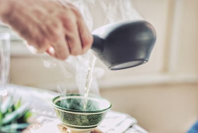 Close-up of hand pouring tea cup