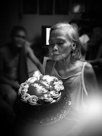 Senior woman with birthday cake at home