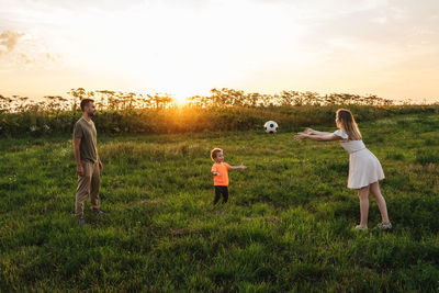 People standing on field against sky during sunset