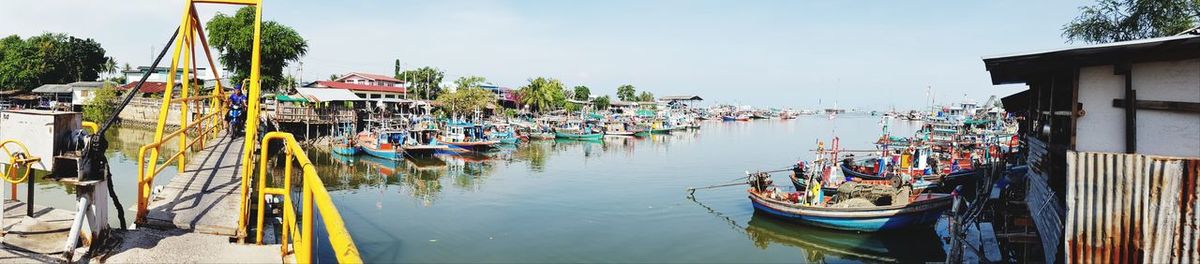 Panoramic view of boats moored in canal by buildings against sky