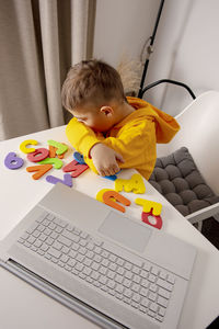 Little boy learning alphabet and numbers online, with laptop at home. child is sad and tired. 