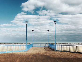 Empty pier by sea against sky