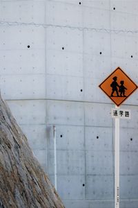 Close-up of children crossing road sign against wall