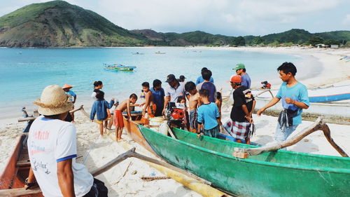 People on boats in sea against sky
