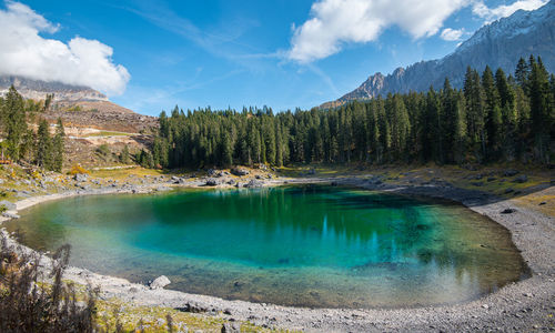 Lake carezza with deep blue colored water and the dolomite mountain range in italy, europe.