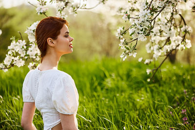 Side view of young woman standing amidst plants