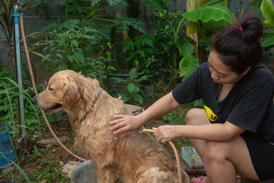 Woman bathing dog in yard