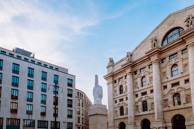 Wide angle view of piazza degli affari in milan with famous artwork in the center