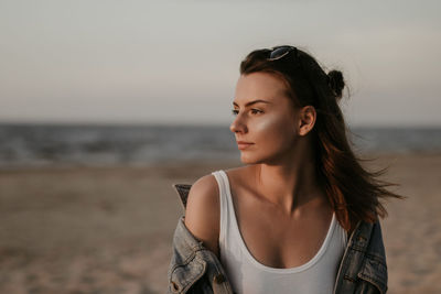 Close-up of young woman against sea during sunset