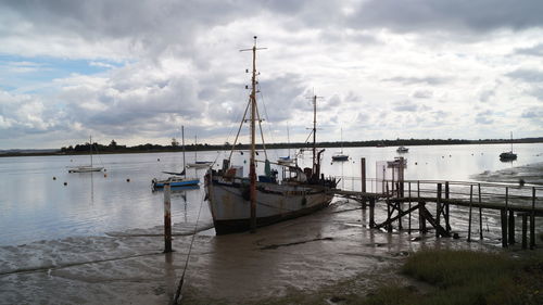 Sailboats moored in sea against sky