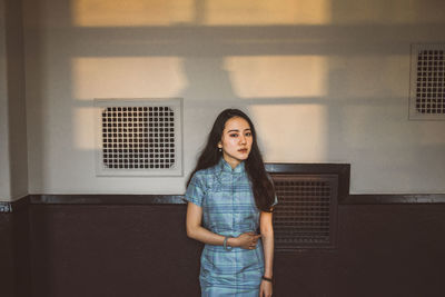 Portrait of woman standing against wall