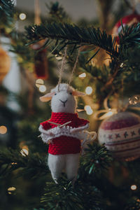 Knitting sheep in a red jumper felt christmas decoration on a christmas tree, shallow focus, bokeh. 