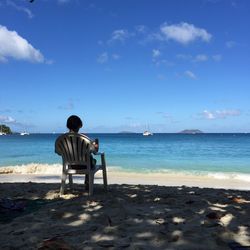 Rear view of men at beach against blue sky