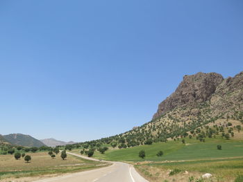 Road amidst landscape against clear blue sky