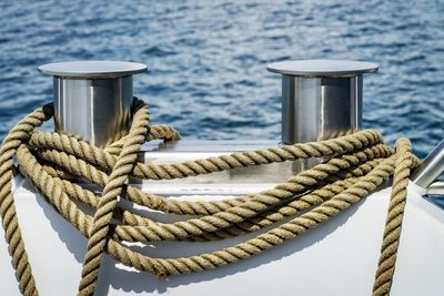 Close-up of rope tied to cleats on boat in sea