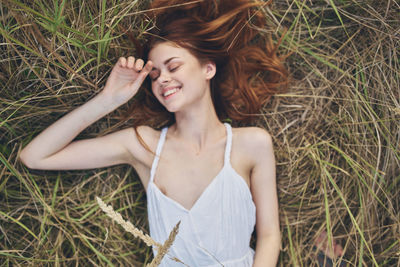 Beautiful young woman lying down on field